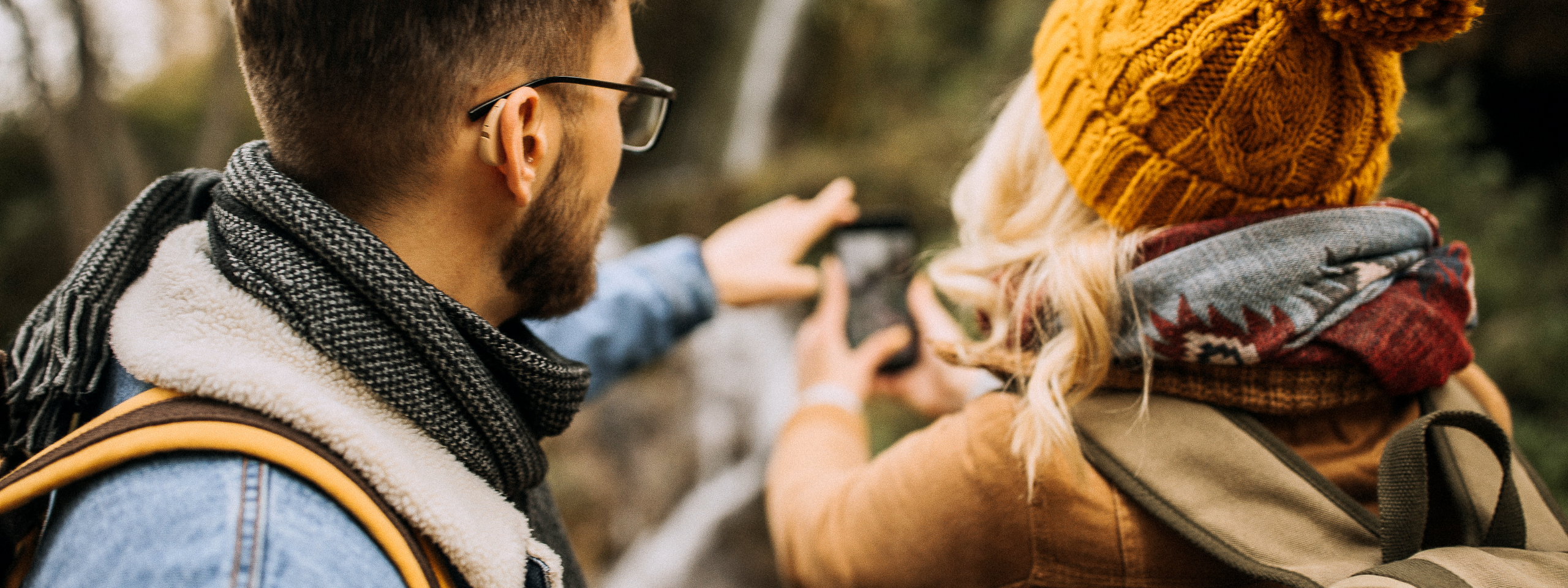 Mann mit Hörgerät und Frau machen Foto in der Natur.